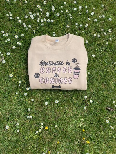 Nude sweatshirt with 'Motivated by coffee and canines' design 